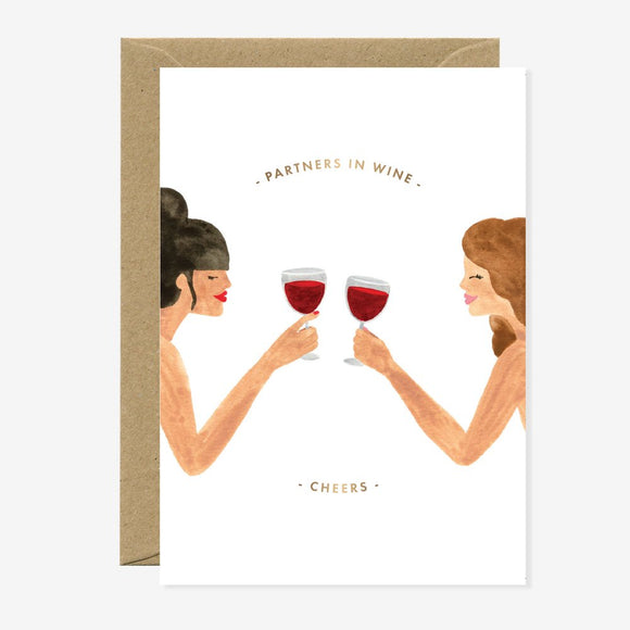 A greeting card with two illustrated women toasting wine glasses with the text 'Partners in wine. Cheers' and a brown envelope.