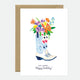 A birthday greeting card with a floral design in a boot, with a 'Happy Birthday' text, presented with a brown envelope.