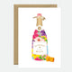 A greeting card featuring a colorful illustration of a champagne bottle with gold foil details and a brown envelope.