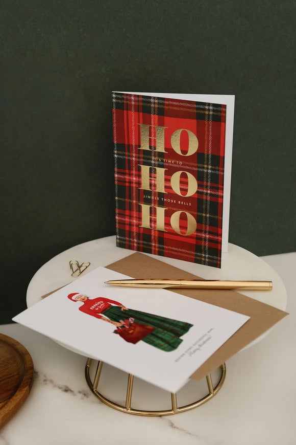 Christmas cards and notebooks styled on marble desk with festive red and green tones, featuring Ho Ho Ho plaid card and elegant gold pen — All the Ways to Say stationery collection.