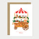 Greeting card featuring a festive dessert cart filled with gingerbread, cakes, and Christmas treats under a red-and-white canopy.