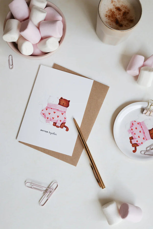 Greeting card Better Together Cats by All the Ways to Say featuring two cats in a pink heart sweater. Illustrated love card with kraft envelope.