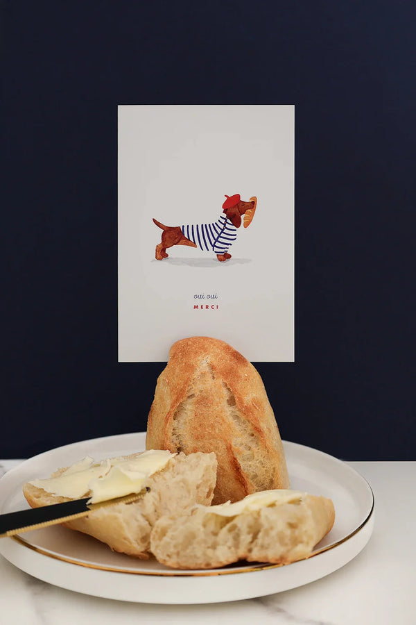 Oui Oui Merci greeting card by All The Ways To Say – French dachshund illustration with baguette and butter on dark blue background