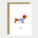 Greeting card with a dachshund wearing a striped shirt and red beret, carrying a baguette in its mouth, with the words "Oui Oui Merci".