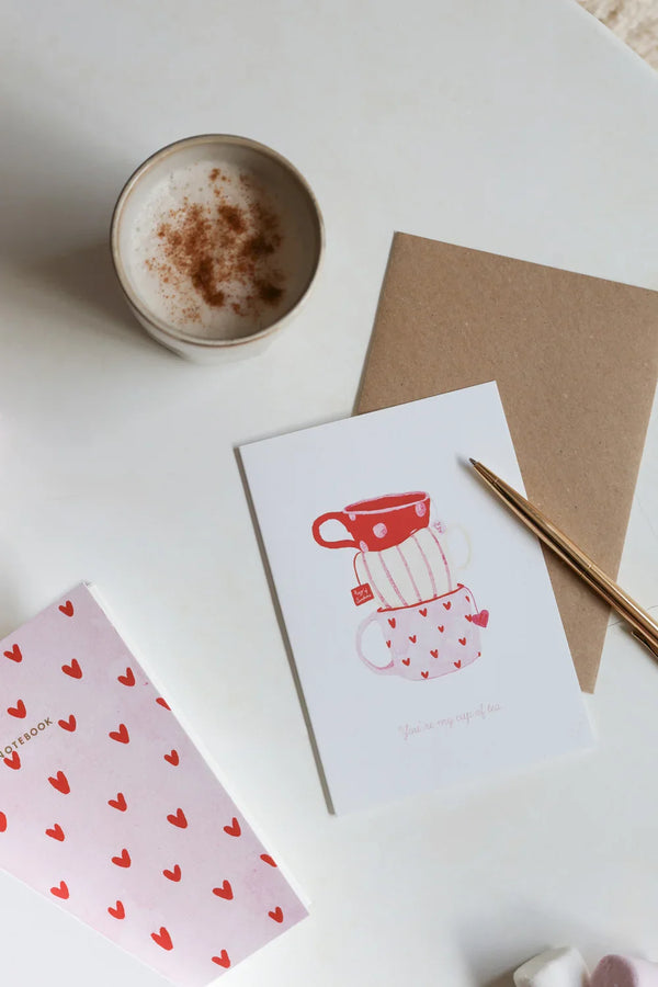Greeting card Cup of Tea by All the Ways to Say with stacked red and pink mugs decorated with hearts. Illustrated love card with kraft envelope.