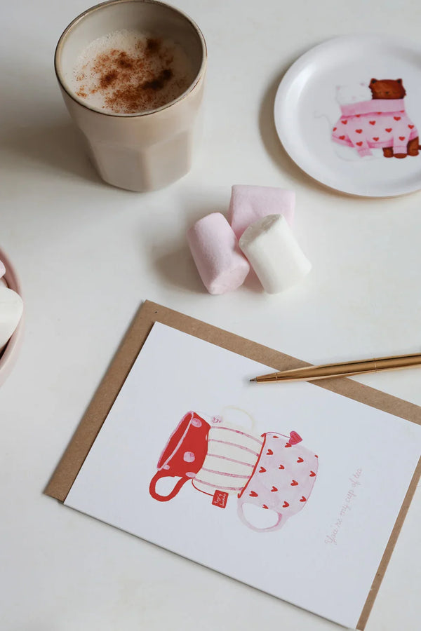 Greeting card Cup of Tea by All the Ways to Say featuring three tea cups in red and pink tones with heart motifs. Illustrated Valentine card with kraft envelope.