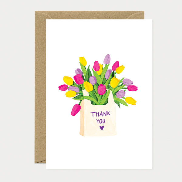 Greeting card with an illustrated tote bag filled with colorful tulips in pink, yellow and purple, with the words “Thank You” written on the bag.