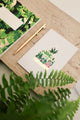 Merci greeting card Greenhouse by All the Ways to Say featuring botanical illustration in a greenhouse with gold foil. Illustrated thank you card with kraft envelope.