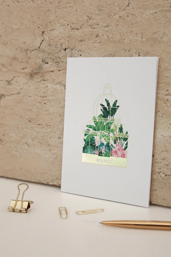 Merci greeting card Greenhouse by All the Ways to Say featuring a lush botanical greenhouse with gold foil details. Illustrated thank you card with kraft envelope.