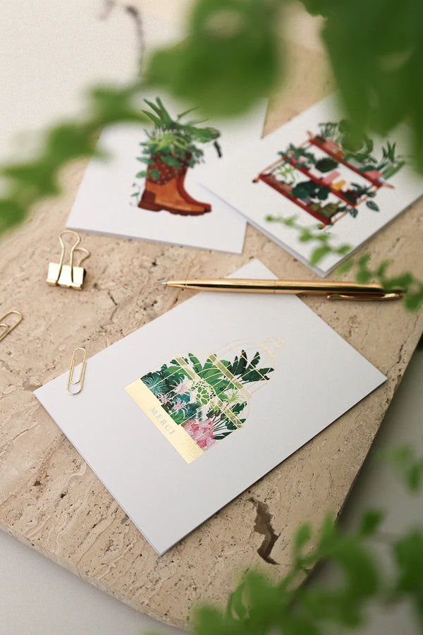 Merci greeting card Greenhouse by All the Ways to Say with tropical plants inside a gold foil greenhouse. Illustrated botanical thank you card with kraft envelope.