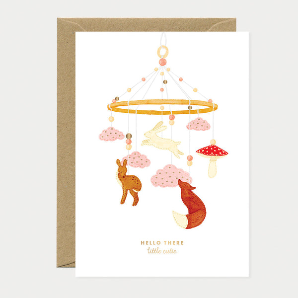 Greeting card showing a baby mobile with animals, clouds, and mushrooms in soft pastel tones, symbolizing tenderness and new beginnings.