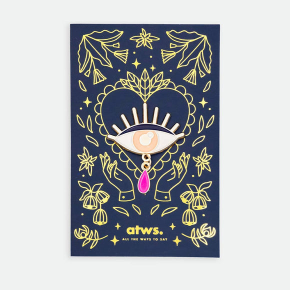Teardrop Eye XL enamel pin by All the Ways to Say featuring gold-plated eye with pink teardrop on navy blue floral mystical background.