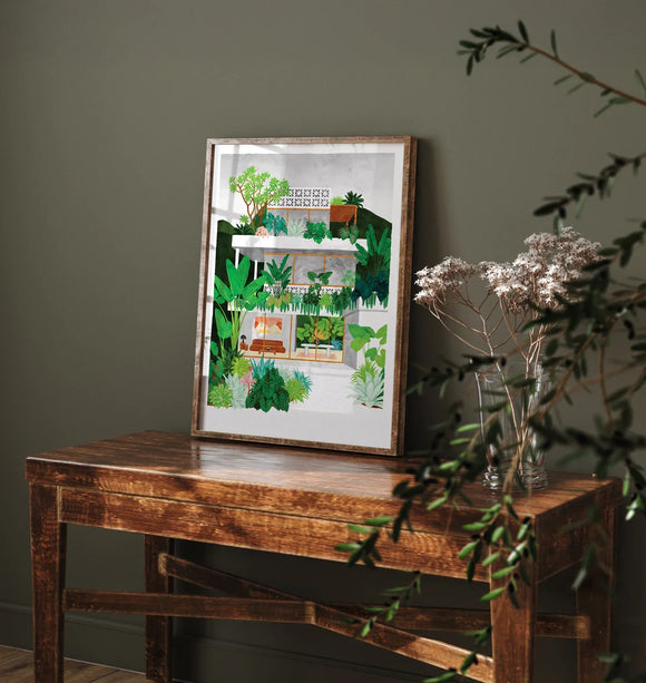 Lombok art print leaning on a rustic wooden table with green plants in a natural interior setting
