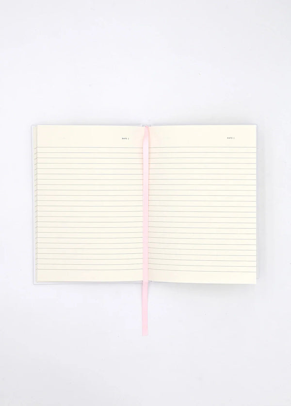 Open Dogue notebook showing lined cream pages with pink ribbon bookmark for writing and journaling.