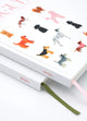 Close-up of Dogue hardcover notebook with illustrated dogs, stacked with another atws journal, ribbon bookmarks visible.