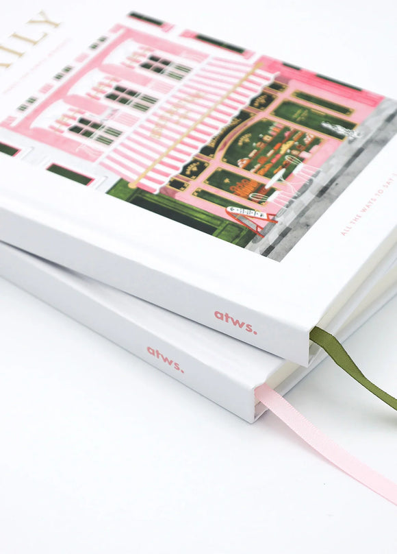 Close-up angled view of Daily bakery notebook cover showing pink striped awning and detailed storefront illustration.