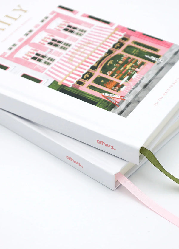 Close-up angled view of Daily bakery notebook cover showing pink striped awning and detailed storefront illustration.