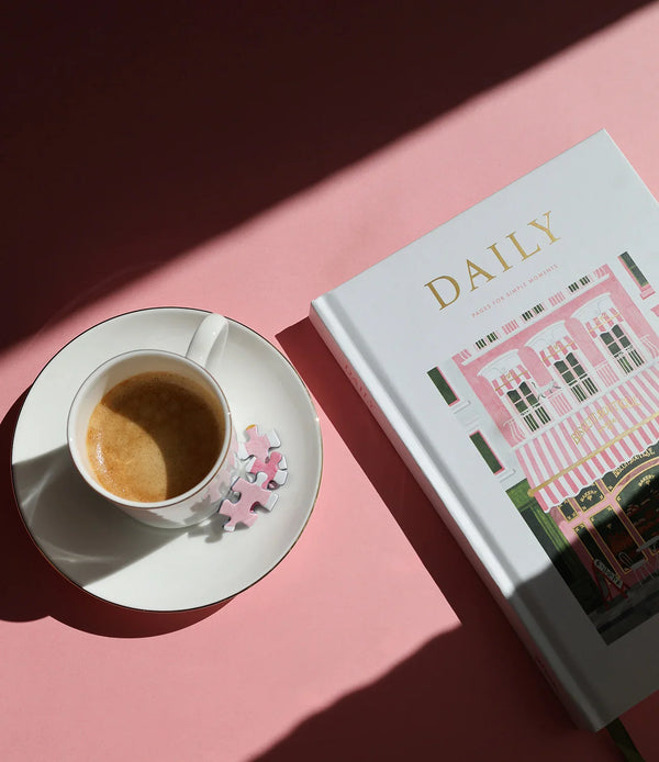 Flat lay of the Bakery Daily Journal, notebook, and greeting card by All the Ways to Say, styled with pastries and coffee on a pink table.