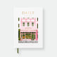 Hardcover notebook A5 with white cover, Paris bakery storefront illustration in pink and green, gold foil “Daily” title and green ribbon bookmark.