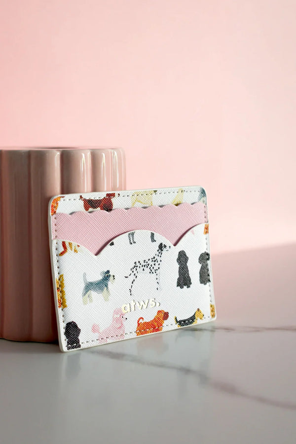 Close-up of dog print card holder with pink scalloped detail, styled against pink ceramic cup on marble surface.