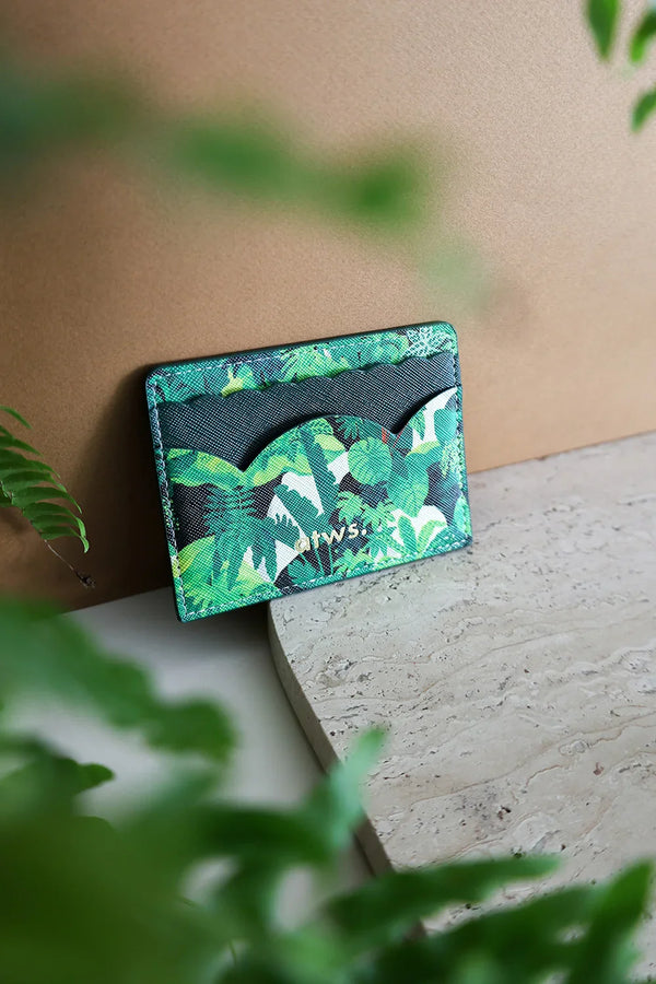 Green Cliff card holder displayed on a stone surface with tropical leaves in the background, elegant botanical pattern by All the Ways to Say.