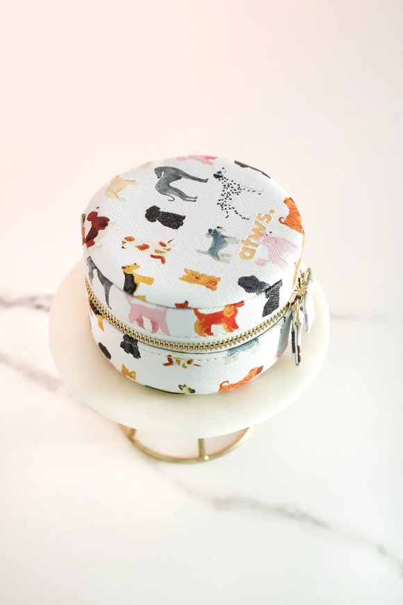 Round jewelry box with colorful dog illustrations, zip closure, displayed on a marble stand