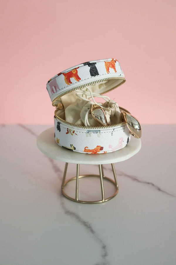 Open round jewelry box with dog pattern, showing interior storage and golden jewelry pieces