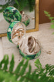 Green tropical jewelry box with leafy pattern, shown open with gold jewelry inside