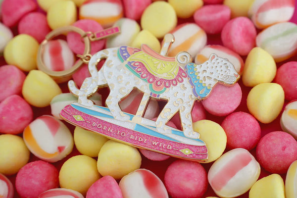 All The Ways To Say Wild Ride enamel keychain – spotted leopard on pink and yellow candy backdrop with pastel saddle
