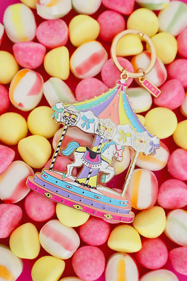 All The Ways To Say carousel keychain with gold details and pastel candy colors – playful flatlay