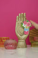 Flower Can keychain by All The Ways To Say displayed on golden hand statue with pink background