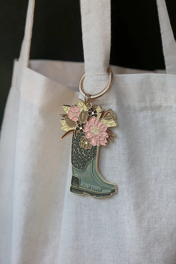 Plant Lover Boots keychain by All The Ways To Say hanging on canvas tote bag – floral enamel boot design