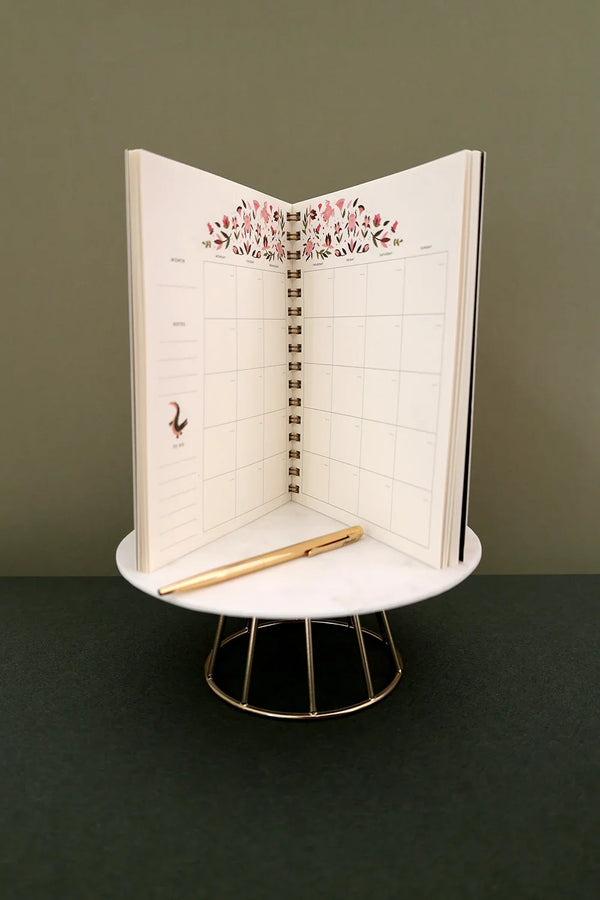 Open Pink Croco monthly planner standing upright showing monthly spread with floral decoration