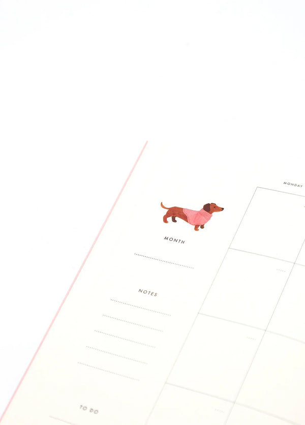 Inside page of Dogue monthly planner featuring a dachshund in a pink sweater with calendar layout