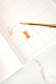 Interior of the Dogue monthly planner with a cute orange dog illustration and gold pen on a white marble surface.