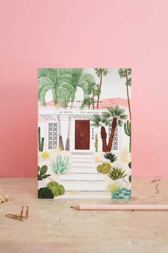 Architectural illustrated notebook with palm trees and desert plants on a pink background, styled with pencil and gold clips.