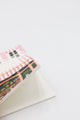 Open dotted notebook with illustrated pink bakery storefront cover, showing clean interior pages on a white background.
