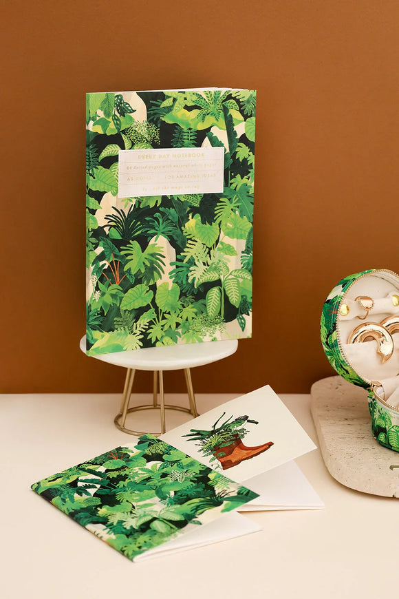 Everyday notebook Green Cliff by All the Ways to Say with lush tropical leaves pattern surrounded by green plants on a beige marble desk.