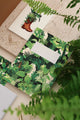 Close-up of Green Cliff notebook by All the Ways to Say featuring vibrant green jungle leaves design with gold details on a beige stone background.
