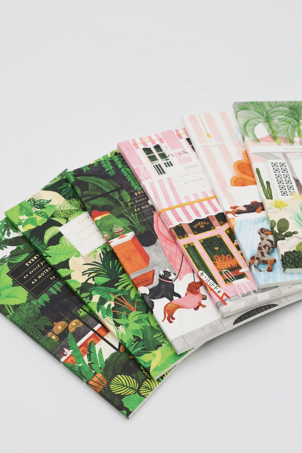 Collection of illustrated A5 notebooks with colorful covers, featuring botanical, architectural, and playful dog designs.