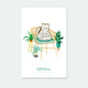 Feline Good enamel pin by All the Ways to Say featuring white cat with “Feline Good” text, gold-plated details, displayed on cozy chair with green plants background.