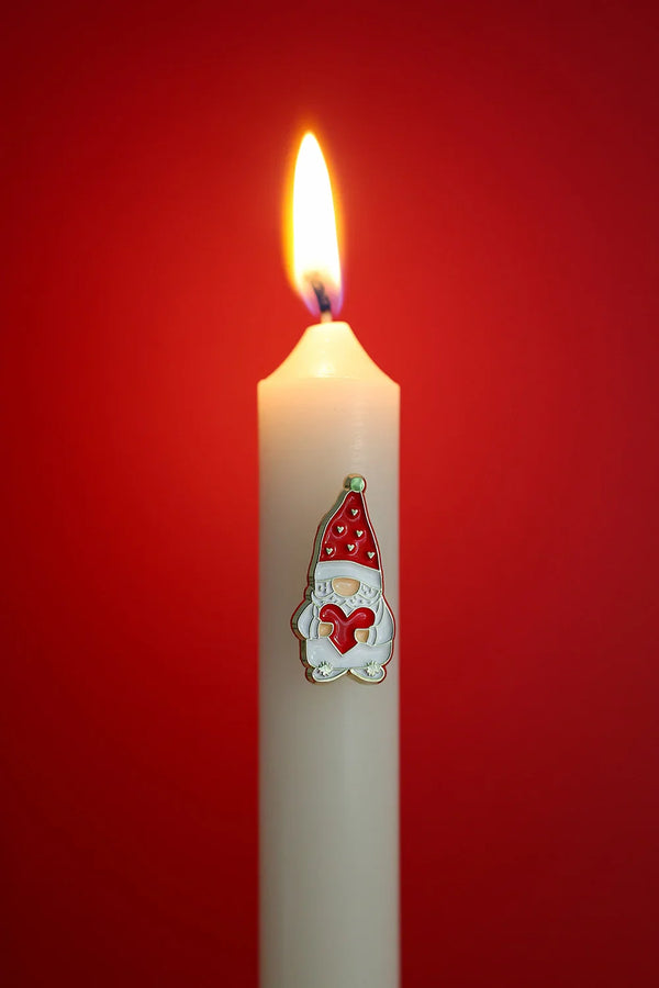 Grumpy Heart enamel pin by All The Ways To Say on white candle with red background – festive Christmas mood