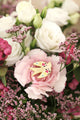 Lovebird enamel pin by All The Ways To Say among pink carnations and white roses – romantic floral flatlay