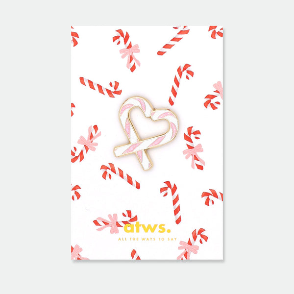 Sugar Heart enamel pin by All the Ways to Say featuring pink and white candy cane heart design with gold-plated details on festive candy background.