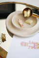 Pink Nutcracker enamel pin by All The Ways To Say on ceramic plate with chocolate and brass scoop – elegant holiday setup