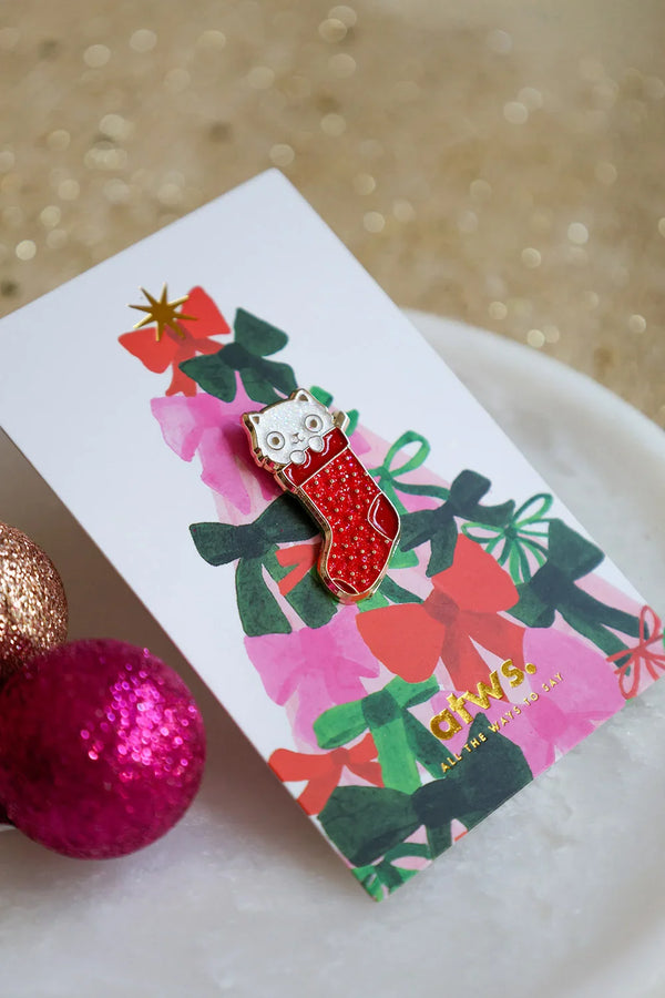Close-up of Cat Sock enamel pin by All The Ways To Say – red stocking with cute cat face, holiday edition