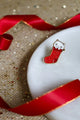 Cat Sock enamel pin by All The Ways To Say – red stocking design photographed with red ribbon on glitter background
