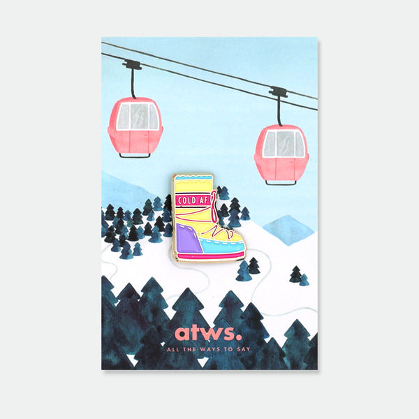 Moon Boots enamel pin by All the Ways to Say featuring colorful winter boot design with “Cold AF” text, gold-plated details on snowy background.