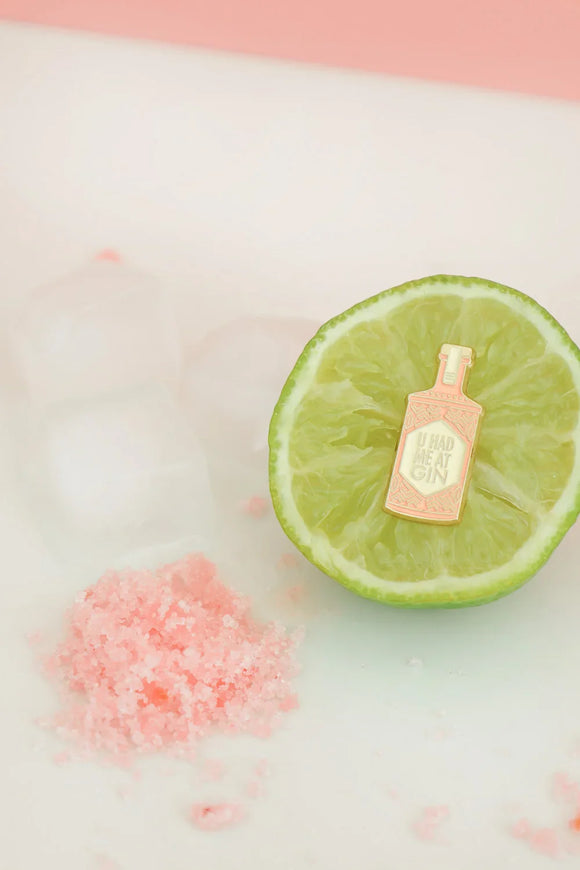 Close-up of U Had Me at Gin enamel pin by All The Ways To Say – gold and pink gin bottle on lime slice with ice and pink salt