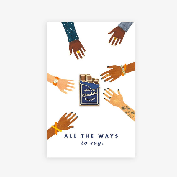 Chocolate Addict enamel pin by All the Ways to Say featuring bitten chocolate bar design with gold-plated details on illustrated hands background.